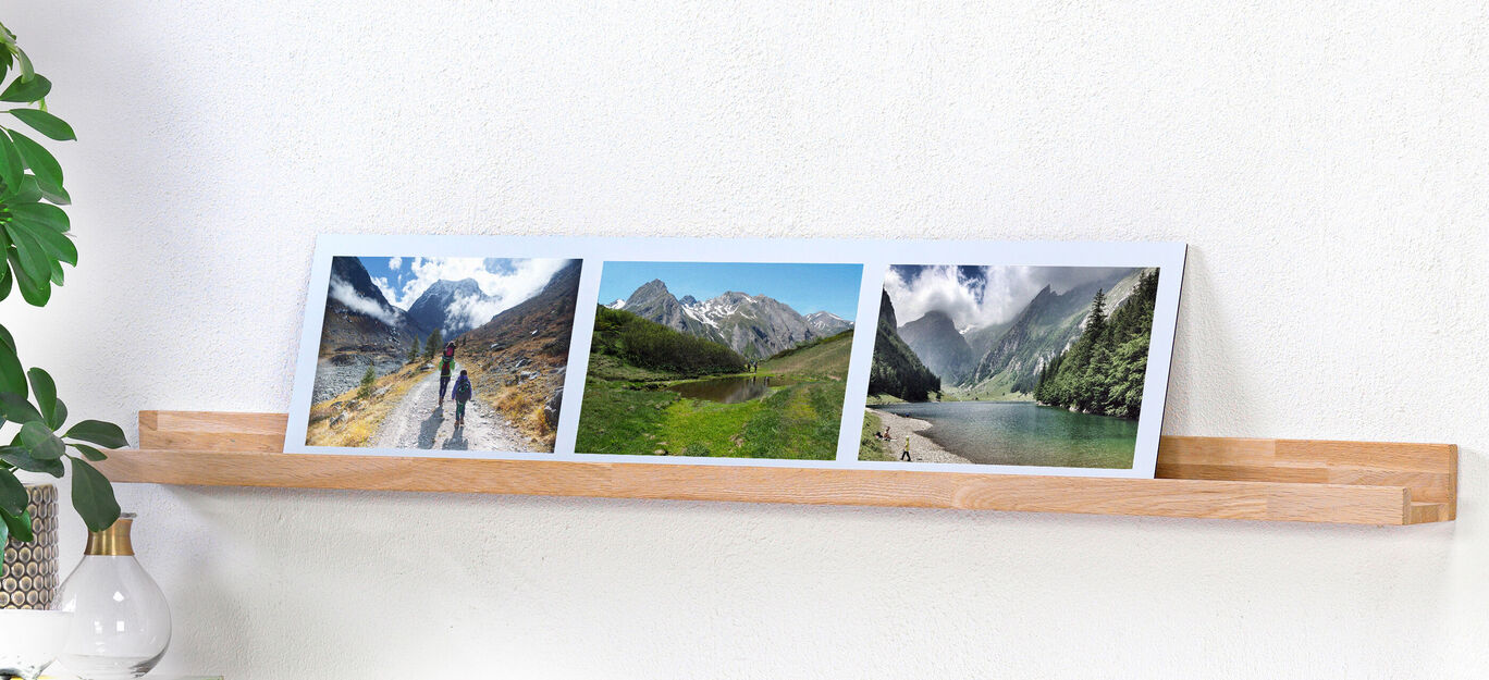 Tres marcos con motivos de paisajes en una estantería de madera, mostrando momentos de naturaleza y viaje.