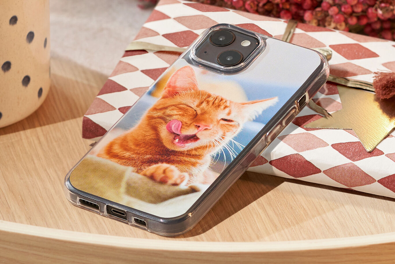 funda de móvil personalizada apoyada en un regalo con la foto de un gato en el reverso.