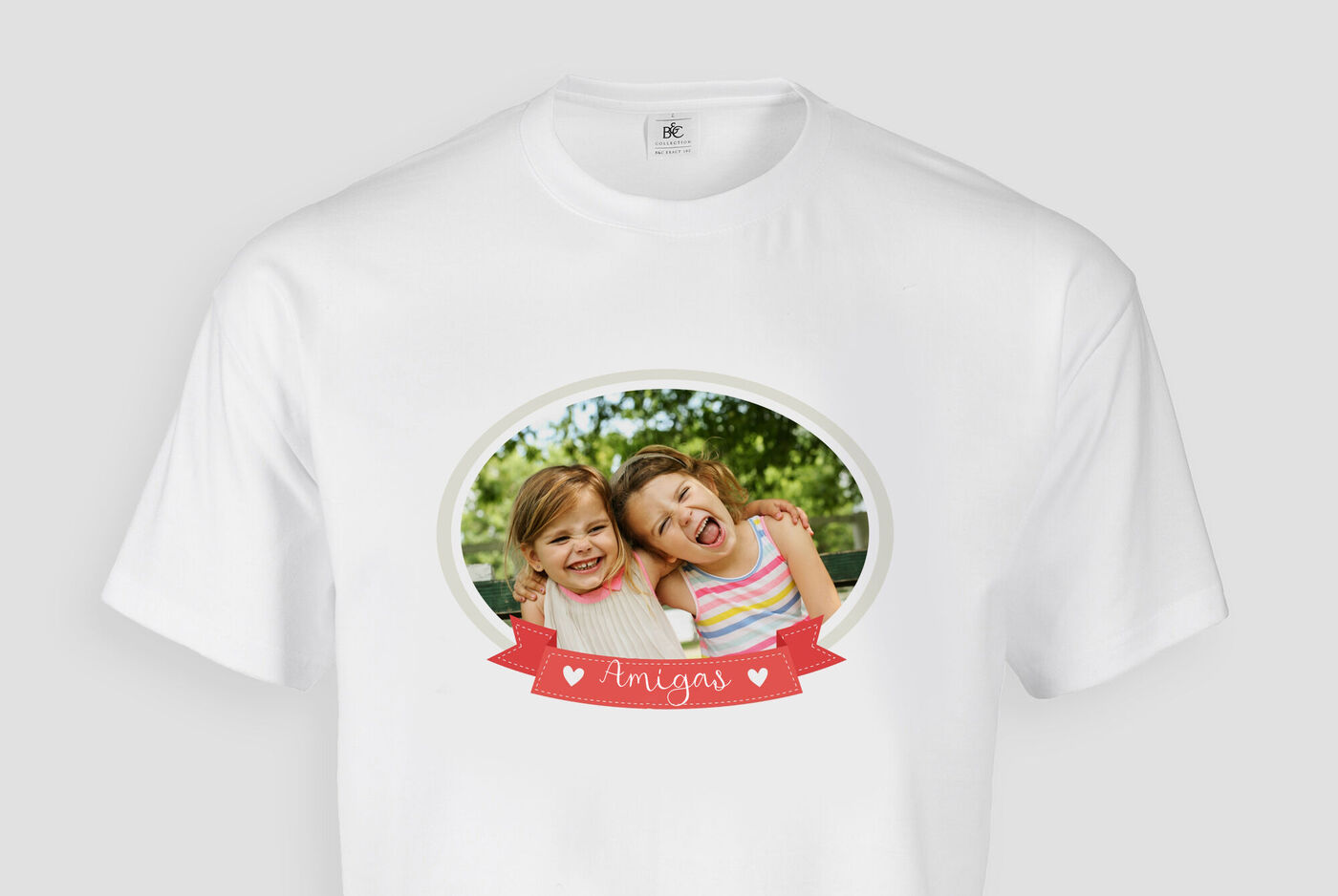 Dos niñas felices abrazándose bajo un árbol con camisetas coloridas. Irradian amistad y alegría.
